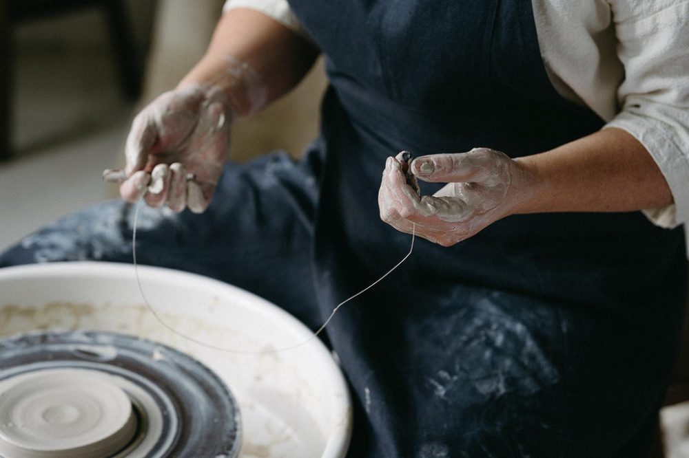 Person wearing navy pottery smock working clay