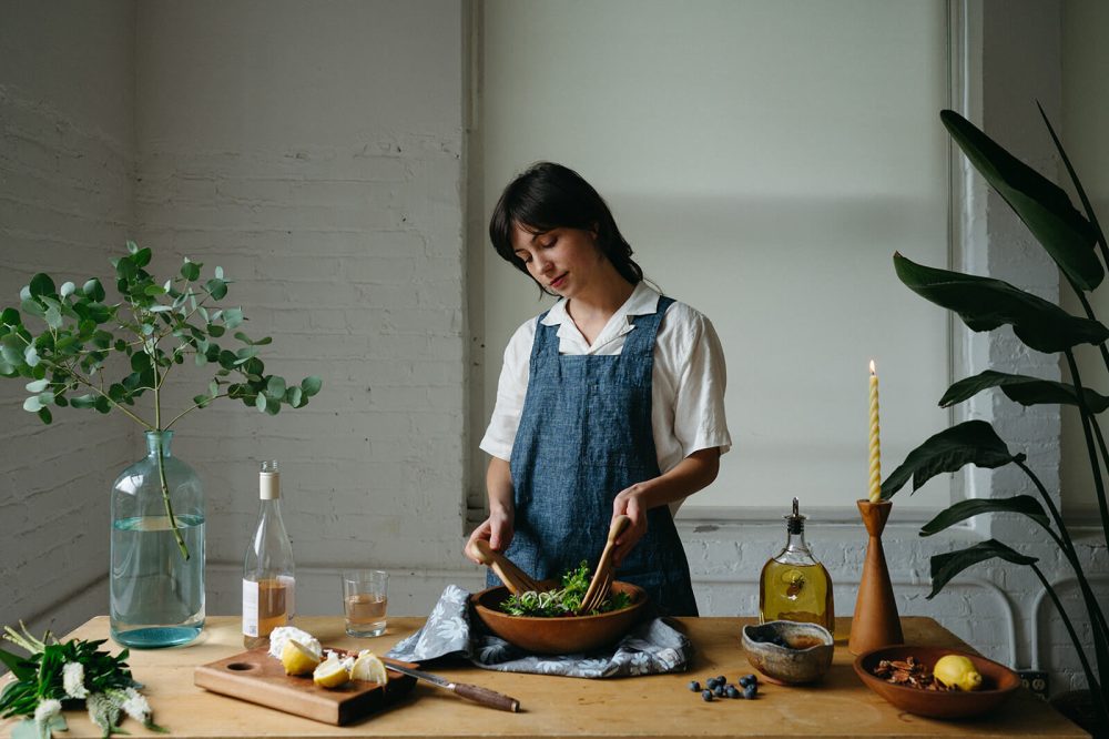 Woman wearing smock apron tossing salad